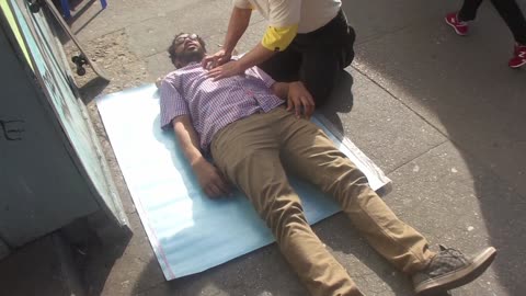 Luodong Massages Black Man On Sidewalk In Plaid Shirt
