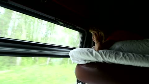 Young girl looking out the train window at nature