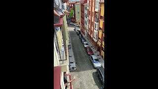 Man in Italy pours a drink for his neighbor two floors below
