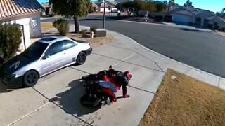 Biker struggles to lift up her motorcycle
