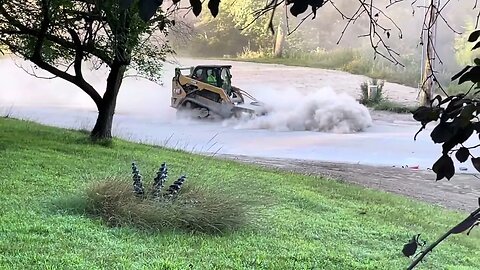 Making a mini dust storm trying to clean the street with a skid loader. Road Construction Project.