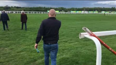 Man jumps horse race hurdle