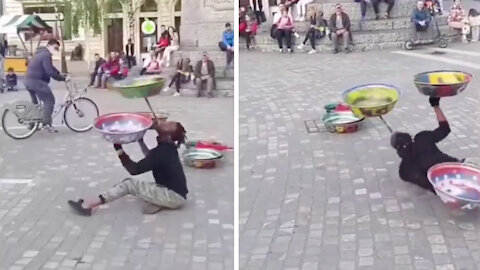 Man spins 3 bowls in the square