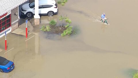 Man attempts to ride bike in flood waters