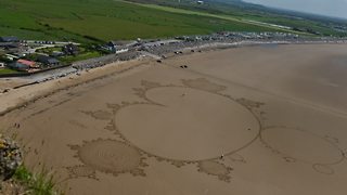 Sand artist uses entire beach to create incredible drawing