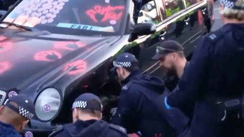 Protesters chainned thire arms together under car police remove wheels more police than protesters