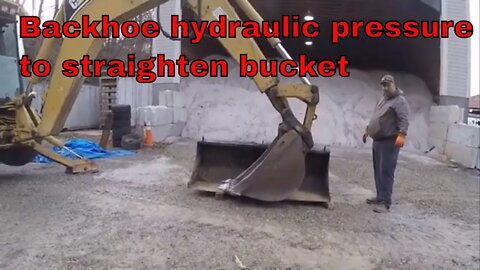 Bent loader bucket using a backhoe to straighten