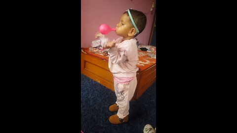 Baby girl is trying to blow a balloon, but couldn’t make and looks so cute.
