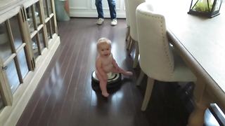 "A Baby Boy Rides on A Roomba Vacuum Cleaner"