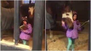 Gullig flicka läser en saga för en häst varje dag