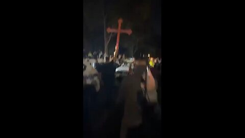 Christians hold up a cross outside the jail where a terrorist is being held for stabbing Bishop