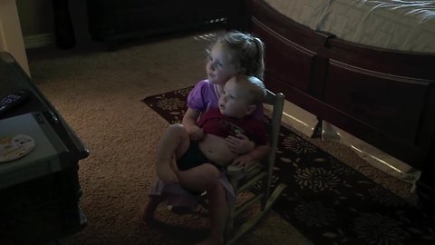 Little Girl Preciously Holds Baby Brother To Watch TV