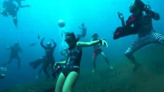 Gruppo di giovani balla sott'acqua, in maschera