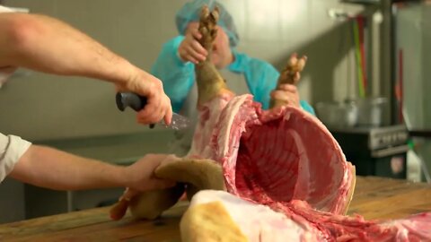 Butcher at a meat factory cutting pork meat Fresh raw pork carcass on table Meat processing in foo