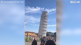 Guy gives playful high fives to tourists at Leaning Tower of Pisa