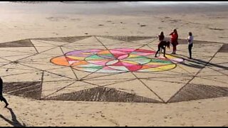 Família cria obra de arte no areal de uma praia