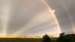 Raggi di sole, fulmini e l'arcobaleno in un unico paesaggio