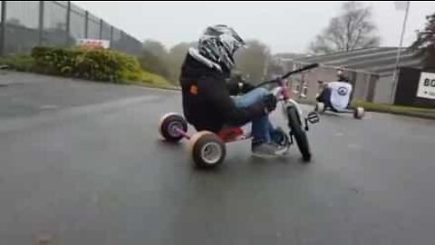 Joukko nuoria ajaa drift trike -pyörillä alamäkeen englantilaisella kadulla