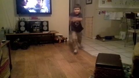 A Dog Imitates A Young Boy Sliding On A Hardwood Floor