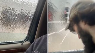 Man breaks sheet of ice on car's window with his head