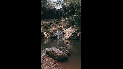 Woman swimming near a stunningly beautiful waterfall