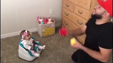 Baby laughs along to her dad's juggling act