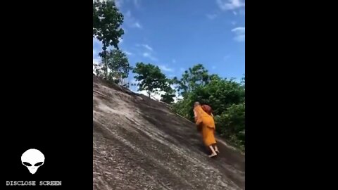 A Monk casually walks vertically past tourist mountain climbers bare foot.