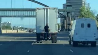 Homem pega carona pendurado na traseira de caminhão