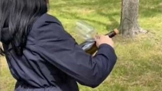 Mulher abre garrafa de champanhe com uma taça