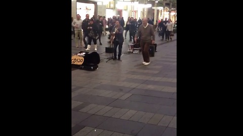 Elderly gentleman dances to street performer