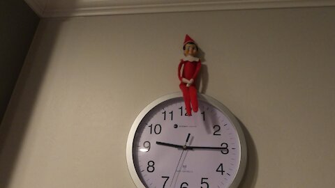 Elf on the Shelf sits on Clock
