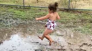 Little girl has great fun in muddy puddle