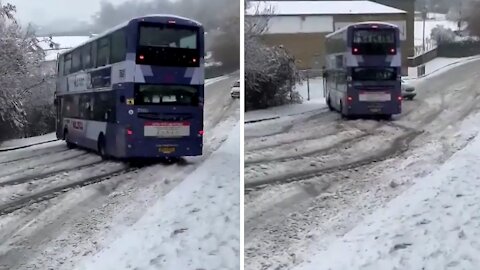 Double decker bus skids in the snow right at another car