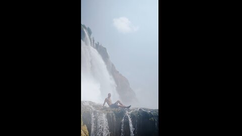 Man Sitting in Front of a Waterfall