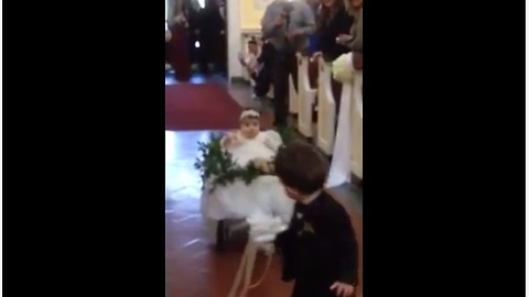 Ring Bearer Pulls Flower Girl Down The Aisle In Wedding Wagon