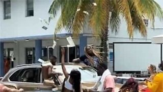 Crazy guy throws dollar bills into the air on Miami street