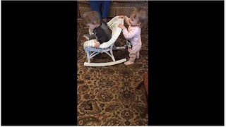 Baby girl pushes twin brother in rocking chair