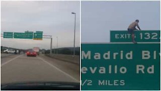 Alabama: uomo in costume si arrampica sul cartello stradale in autostrada