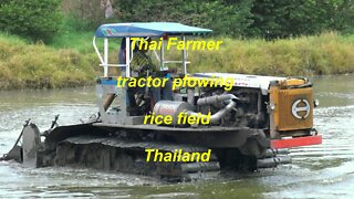 Thai farmer tractor plowing rice field Thailand