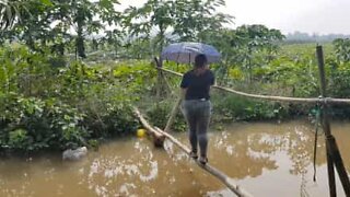 Young woman tries to cross "monkey bridge" over a river