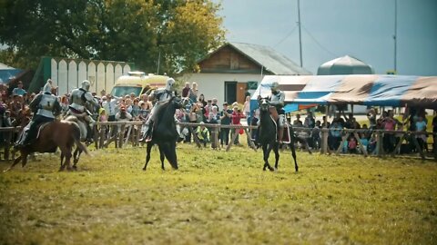 Knights having a battle on the field - the judge walking around and watching the battle- people watc