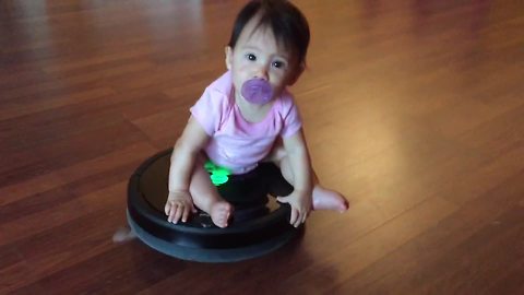 A Baby Girl Having Fun Riding A Roomba Vacuum