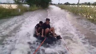 Vänner åker wakeboard på översvämmade gator i Thailand