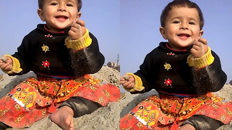 Naughty Baby Playing On The River Corner With Sand