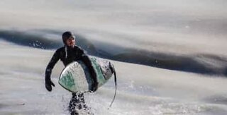 Surfere prøver at surfe på frosne bølger i Massachusetts