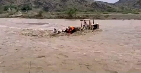 Rescue of people from a flooded car on a bulldozer. A stormy river that overflowed