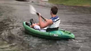 Il profite des rues inondées pour faire du kayak