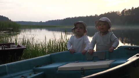 Cute twins in bucket hats happily playing with a boat at the lake Special moments of life
