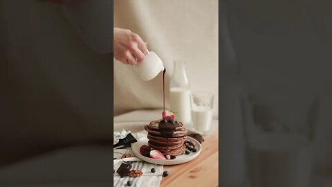 A Person Pouring Chocolate Syrup on Pancakes