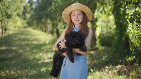Happy teenage girl posing with black Norfolk Terrier in summer spring park on sunny day portrait of